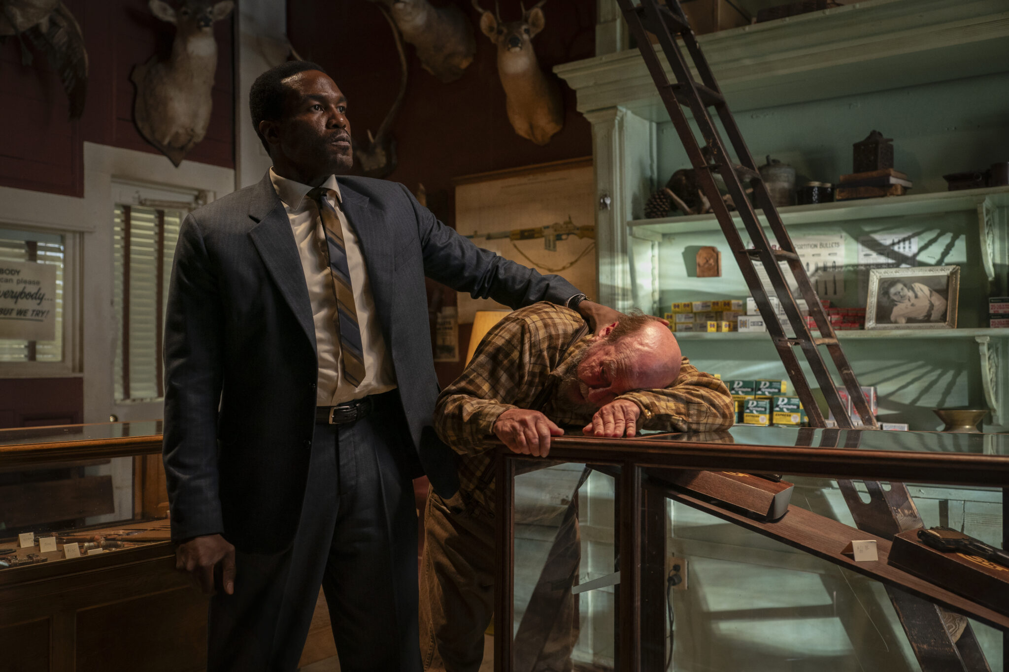 Yahya Abdul-Mateen II restrains a man inside a shop in an official still from By Any Means (2026)
