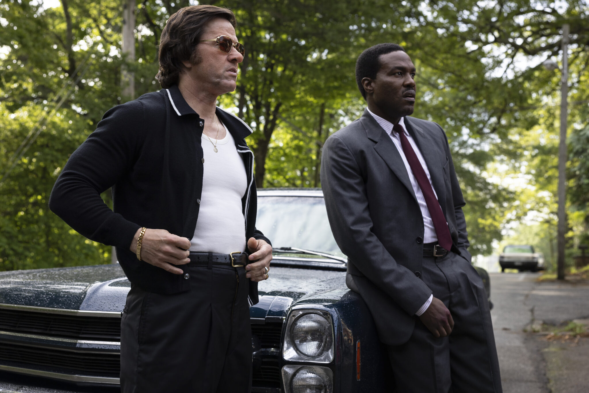 Mark Wahlberg and Yahya Abdul-Mateen II beside a car in an official still from By Any Means (2026)