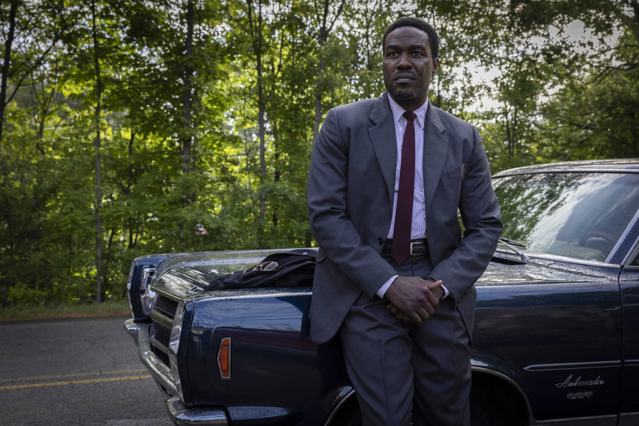 Yahya Abdul-Mateen II beside a car in an official still from By Any Means (2026)