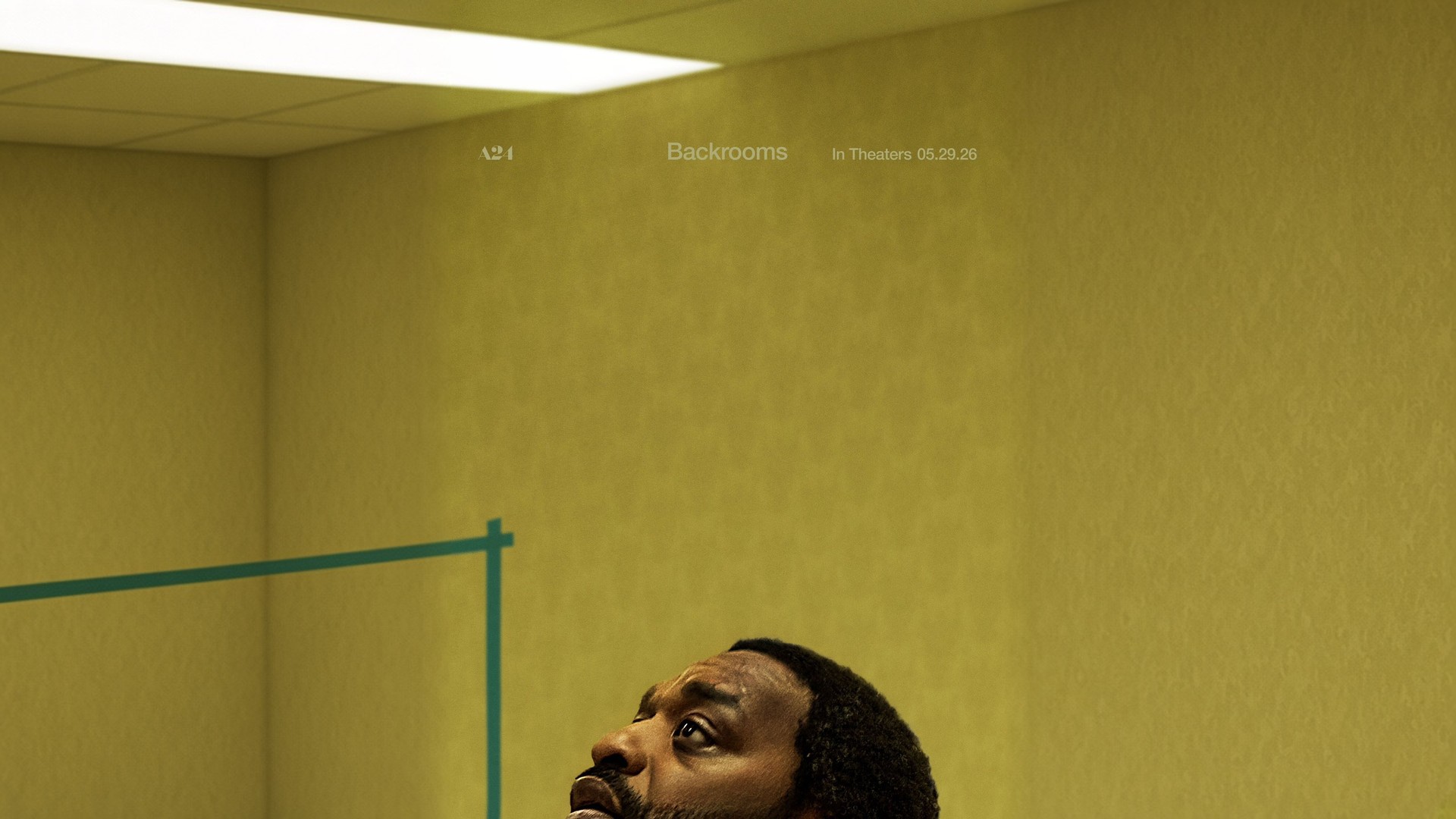 Official Backrooms poster showing Chiwetel Ejiofor looking up in an empty yellow room, widened into a landscape frame