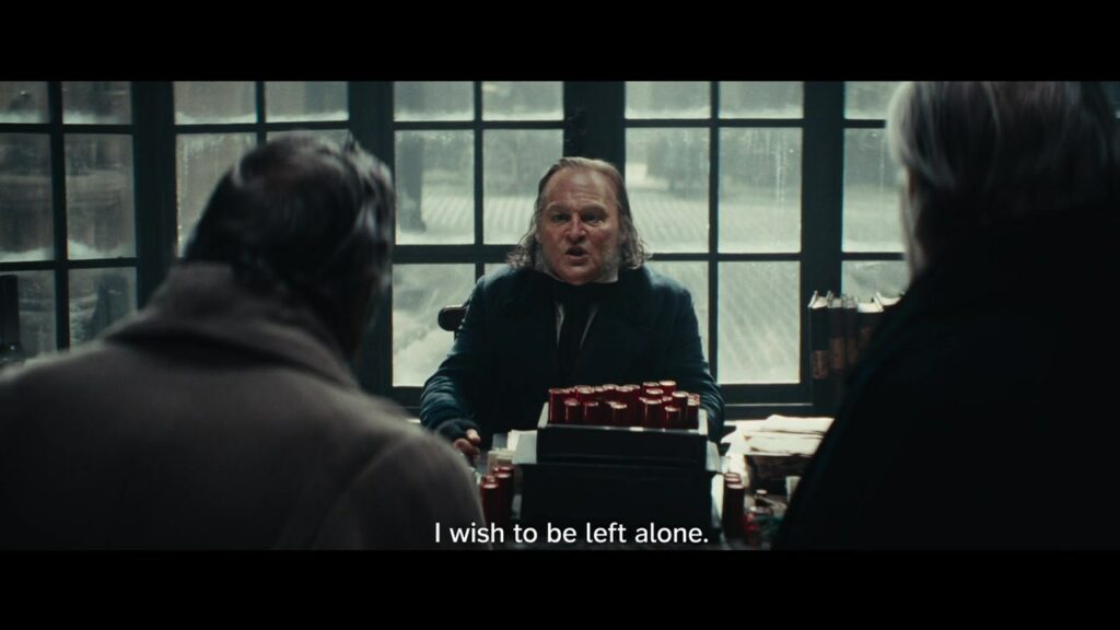 An intact frame from Ebenezer’s second trailer shows Scrooge seated at his desk, with the English subtitle ‘I wish to be left alone.’