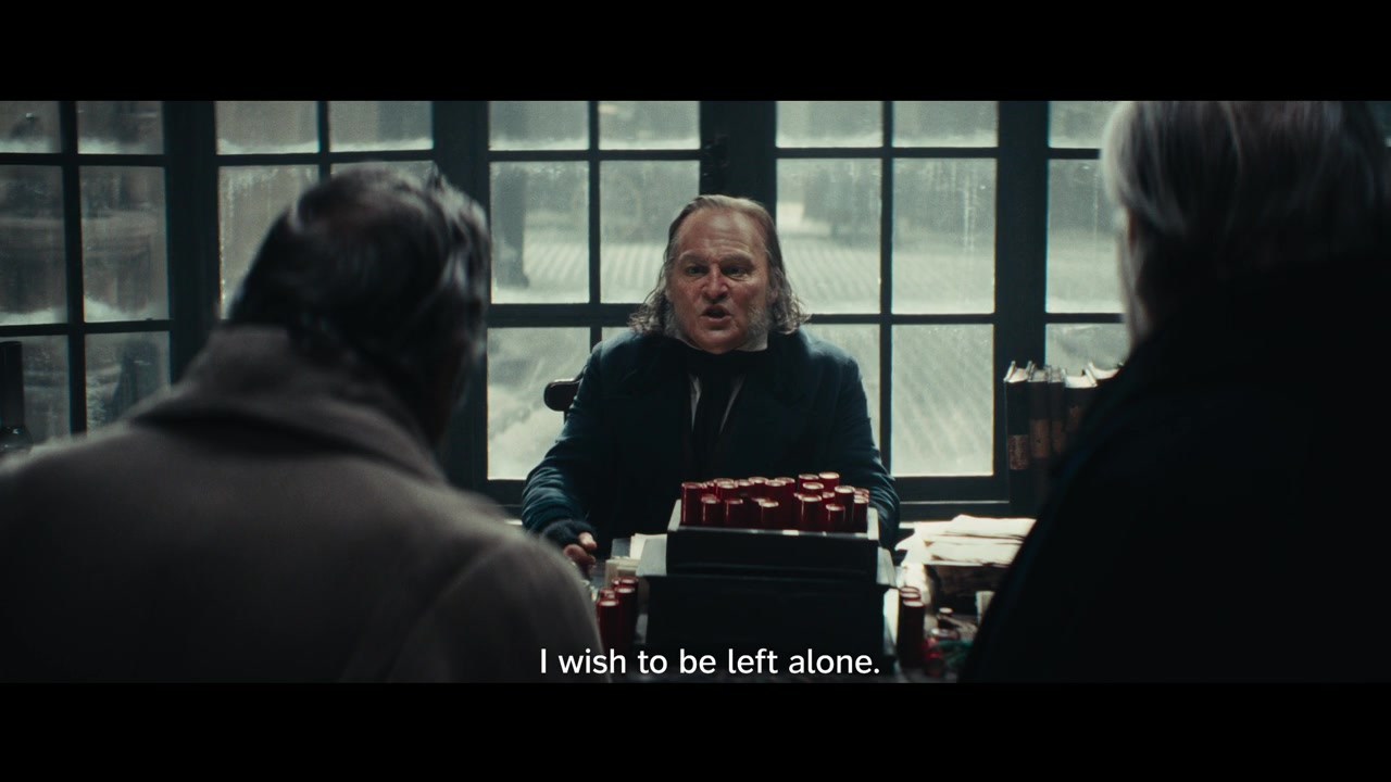 An intact frame from Ebenezer’s second trailer shows Scrooge seated at his desk, with the English subtitle ‘I wish to be left alone.’