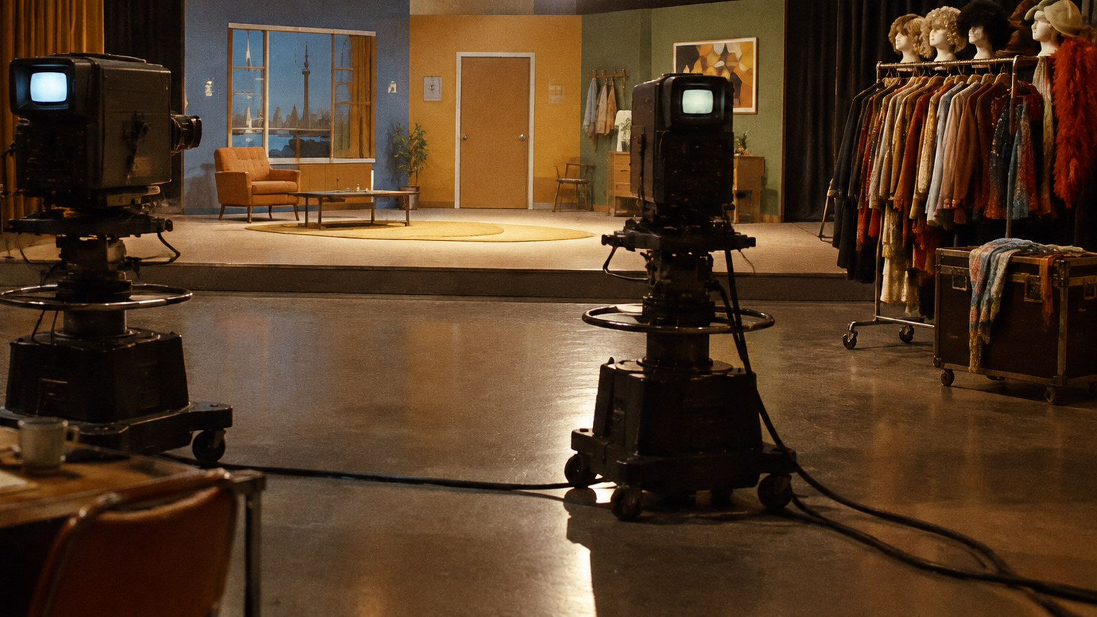 AI artwork: an empty vintage 1970s television studio with two old cameras facing a brightly lit sketch comedy set and a rail of costumes and wigs