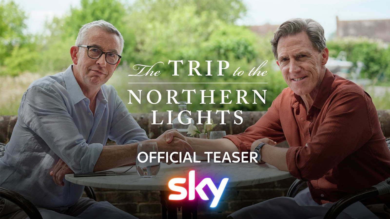 Official Sky key art for The Trip to the Northern Lights: Steve Coogan and Rob Brydon shake hands across a garden table, with the series title between them